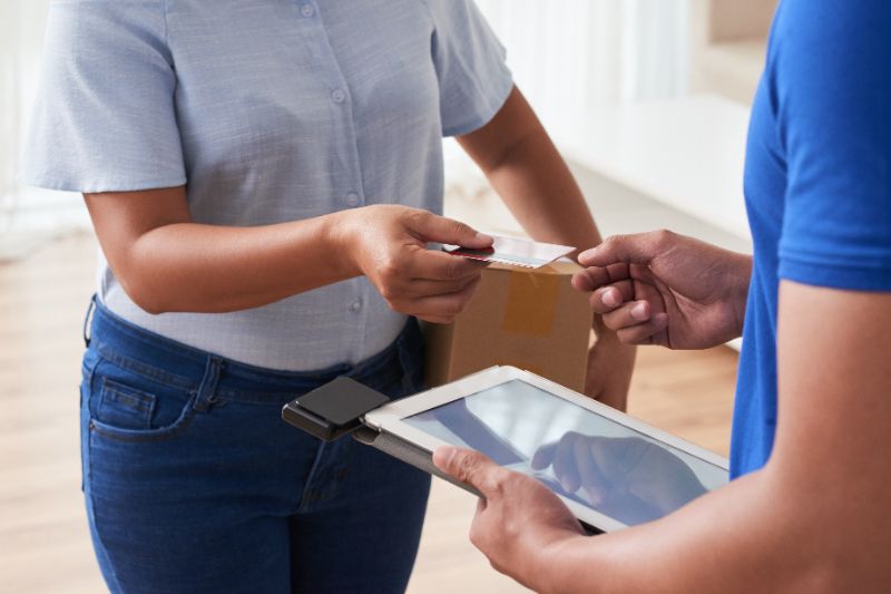 Envelope com cartão de crédito em uma mesa cercado por smartphone, laptop e café em iluminação natural.